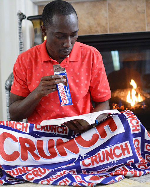 Chris Smith a.k.a. CLS, reading by the fireplace and eating a crunch chocolate bar during a Nestlé Crunch Social Media Partnership.