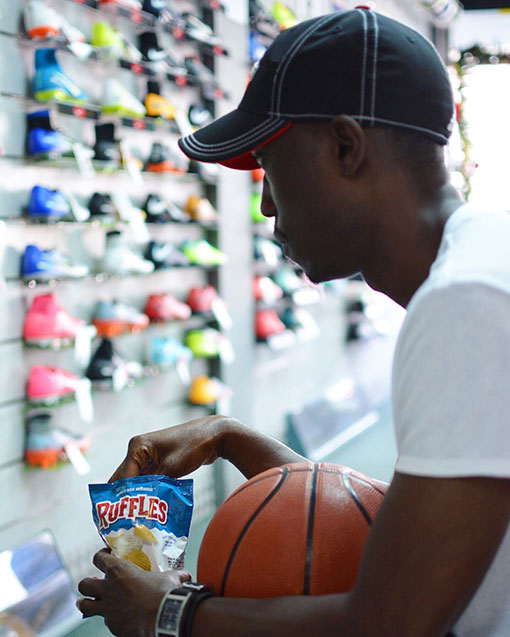 Chris Smith a.k.a. CLS, eating Ruffles while getting sneakers at a sporting goods store for the Ruffles Live Like A Baller Campaign.