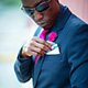 Chris Smith a.k.a. CLS, wearing a navy blue suit and inserting a pocket square in an Instagram post.