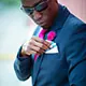 Chris Smith a.k.a. CLS, wearing a navy blue suit and inserting a pocket square in an Instagram post.